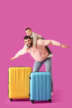 Küçük oğlu ve bavulları menekşe arkaplanlı mutlu bir baba. Seyahat kavramı
