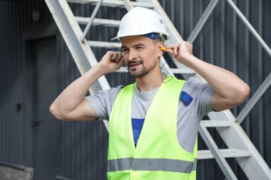 Erkek müteahhit kulak tıkaçları takıyor.