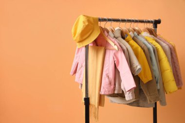 Süslü çocuk kıyafetleri ve turuncu arka planda aksesuarlarla doldur.