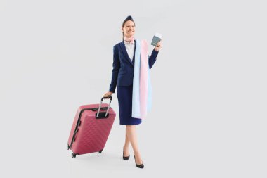 Hafif arka planda transseksüel bayrağı ve bavulu olan genç hostes.