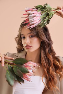 Bej arka planda protea çiçekleri olan güzel genç bir kadın, yakın plan.