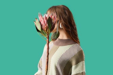 Yeşil arka planda protea çiçekleri olan genç bir kadın.