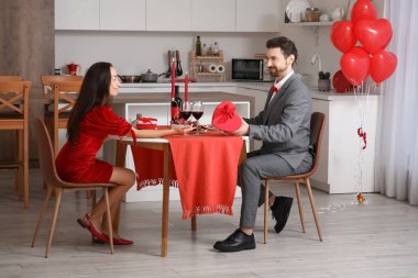 Sevgi dolu bir çift evde şarap, mum ve hediyelerle romantik bir akşam yemeği yiyor. Sevgililer Günü kutlaması