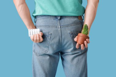 Mavi arka planda kaktüslü ve fitilli adam, yakın plan. Hemoroit konsepti