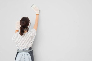 Sırt manzaralı, ışık duvarının yanında macun bıçağı olan bir kadın işçi.