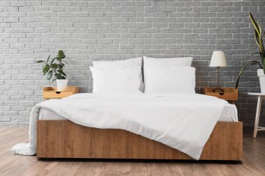 Modern yatak odasının iç kısmında battaniyeli beyaz yastıklar.