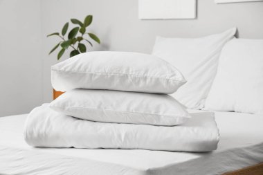 Aydınlık odada beyaz yastıklar ve katlanmış battaniyeler.