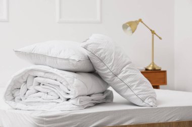 Yumuşak yastıklar, katlanır beyaz battaniyeler, ışık odasında yatağın üstünde.