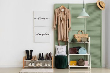 Salonun içinde yeşil katlı ekran, ayakkabı standı ve raf ünitesi var.