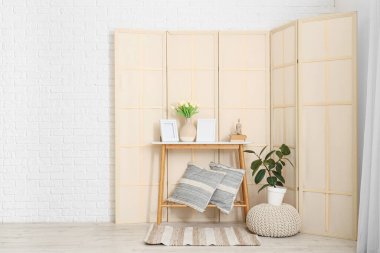 Katlanmış ekran, masa ve puf olan odanın içi