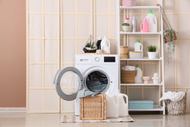 Çamaşır odasının içinde katlanan perde, çamaşır makinesi ve raf ünitesi var.