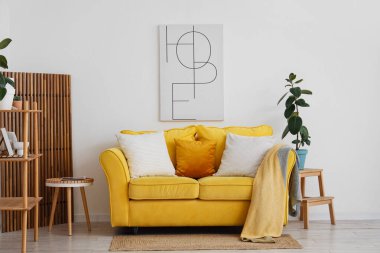 Sarı kanepeli, çiçekli ve masalı aydınlık oturma odasının içi.