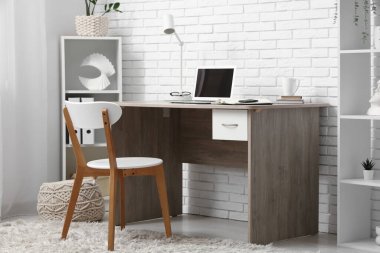 Bilgisayarı ve rafları beyaz tuğla duvarın yanında olan modern ofis.