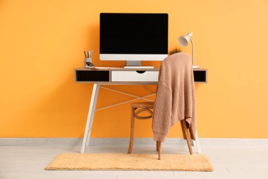 Sarı duvarın yanında bilgisayar olan modern bir işyeri.