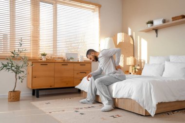 Evde sırt ağrısı çeken genç bir adam.