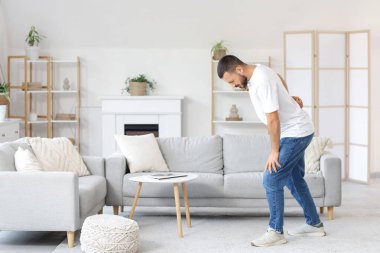 Evde sırt ağrısı çeken genç bir adam.