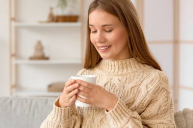 Evde bir fincan çayla genç bir kadın, yakın plan.