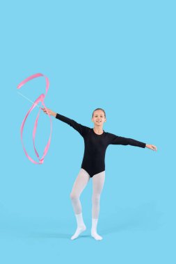 Teenage girl with ribbon doing gymnastics on blue background clipart