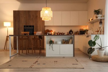 Akşam vakti mutfak masası, tezgahlar ve parlayan lambalar.