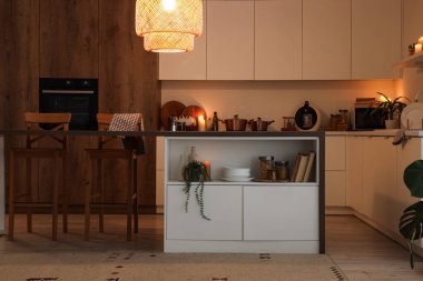 Akşam vakti mutfak masası, tezgah ve parlayan lamba.