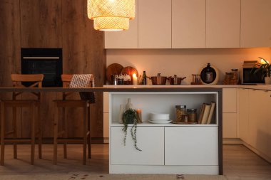 Mutfağın içinde masa, yanan mumlar ve parlayan lambalar var.