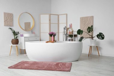 Küveti, lavabosu ve pembe kasımpatı çiçekleri olan şık bir banyo.