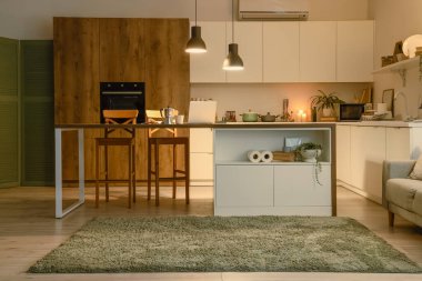 Akşam vakti mutfak masası, tezgahlar ve parlayan lambalar.