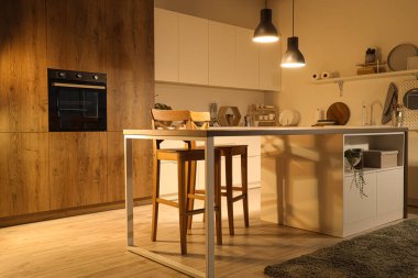 Akşamları masa, tezgah ve parlayan lambalar olan modern mutfak.