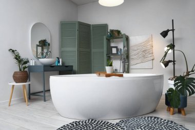 Banyonun içinde küvet, yeşil bitkiler ve parlayan lambalar var.