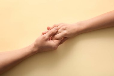 Bej arka planda el ele tutuşan çift, üst görünüm