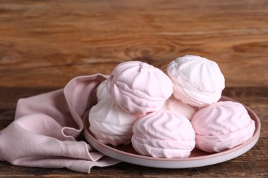 Ahşap arka planda tabakta lezzetli marşmelovlar