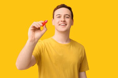 Sarı arka planda dudak merhemi olan mutlu genç bir adam.