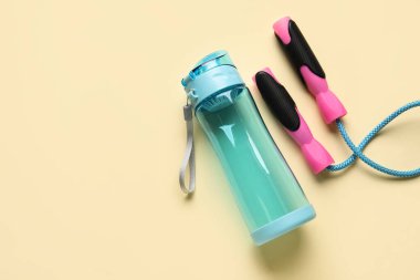 Spor su şişesi ve bej arka planda atlama ipi.