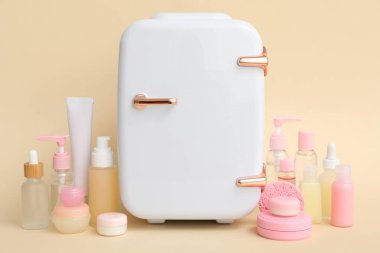 Bej arka planda küçük kozmetik buzdolabı ve kozmetik ürünleri