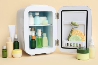 Bej arka planda kozmetik ürünleri olan küçük bir kozmetik buzdolabı