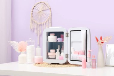 Masada eflatun duvarına karşı kozmetik ürünleri olan küçük bir buzdolabı.