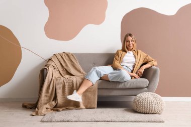 Oturma odasındaki koltukta dinlenen olgun bir kadın.