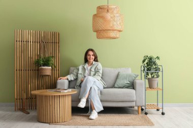 Evdeki gri kanepede dinlenen genç ve güzel bir kadın.