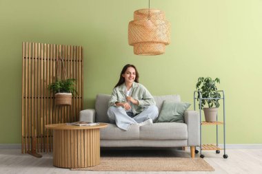 Evdeki gri kanepede dinlenen genç ve güzel bir kadın.