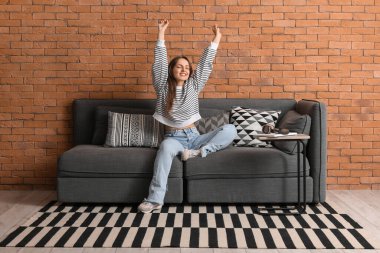 Evdeki siyah kanepede dinlenen genç ve güzel bir kadın.