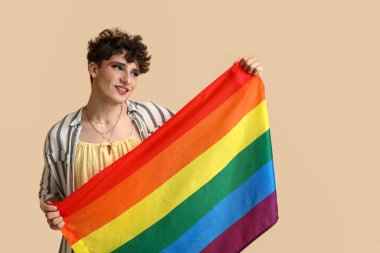 Bej arka planda LGBT bayrağı olan genç transseksüel kadın.