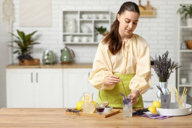 Mutfaktaki masada bir bardak taze lavanta limonatasıyla güzel bir genç kadın.