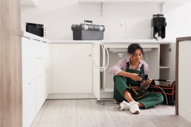 Mutfakta piposu olan Afro-Amerikalı bir tesisatçı.