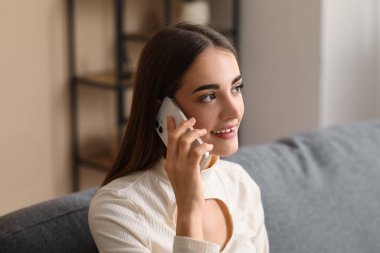 Diastemalı genç bir kadın cep telefonuyla konuşuyor, yakın çekim.