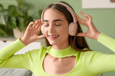 Kulaklık takan, diyabetik hastası, evde müzik dinleyen genç bir kadın.