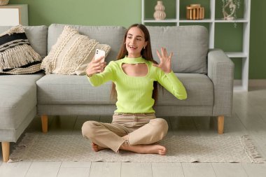 Diastemalı genç bir kadın evde selfie çekiyor.