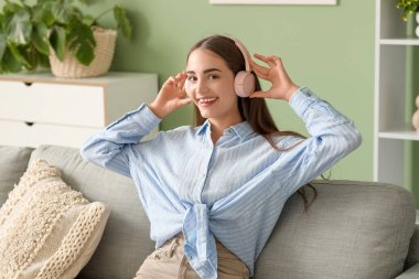 Kulaklık takan, diyabetik hastası, evdeki kanepede oturan genç bir kadın.