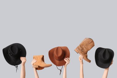 Tarz sahibi kovboy şapkaları ve gri arka planda ayakkabıları olan kadın elleri.