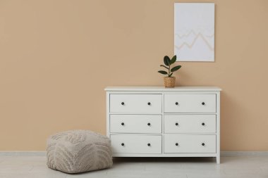 Bej duvarda ve çekmecelerde asılı bir resim.