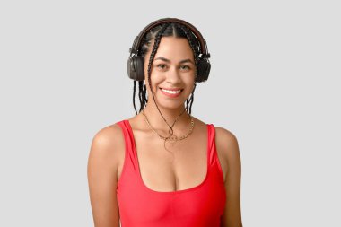 Gri arka planda rastalı kulaklıklı Afro-Amerikan bir kadın.